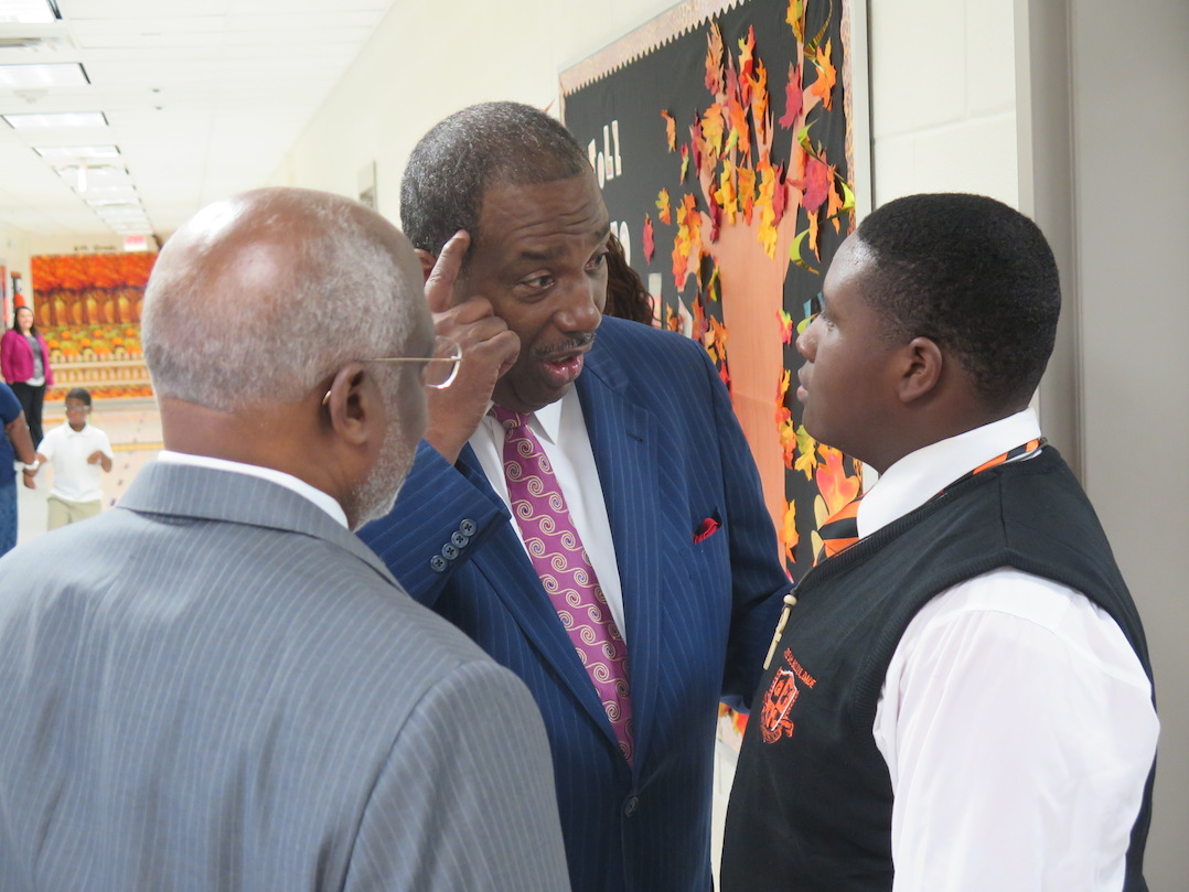 Dale Long and Sen. Royce West talk with a student at Dade Middle School.