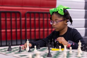 Student with green bow playing chess