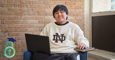 student sitting in chair with laptop and notebook