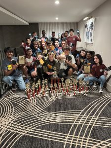 Group of students crouching in a hallway for a photo with their trophies at TMSCA